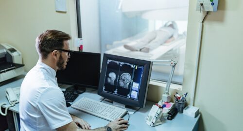 Doctor supervising brain scan procedure of a patient from control room.